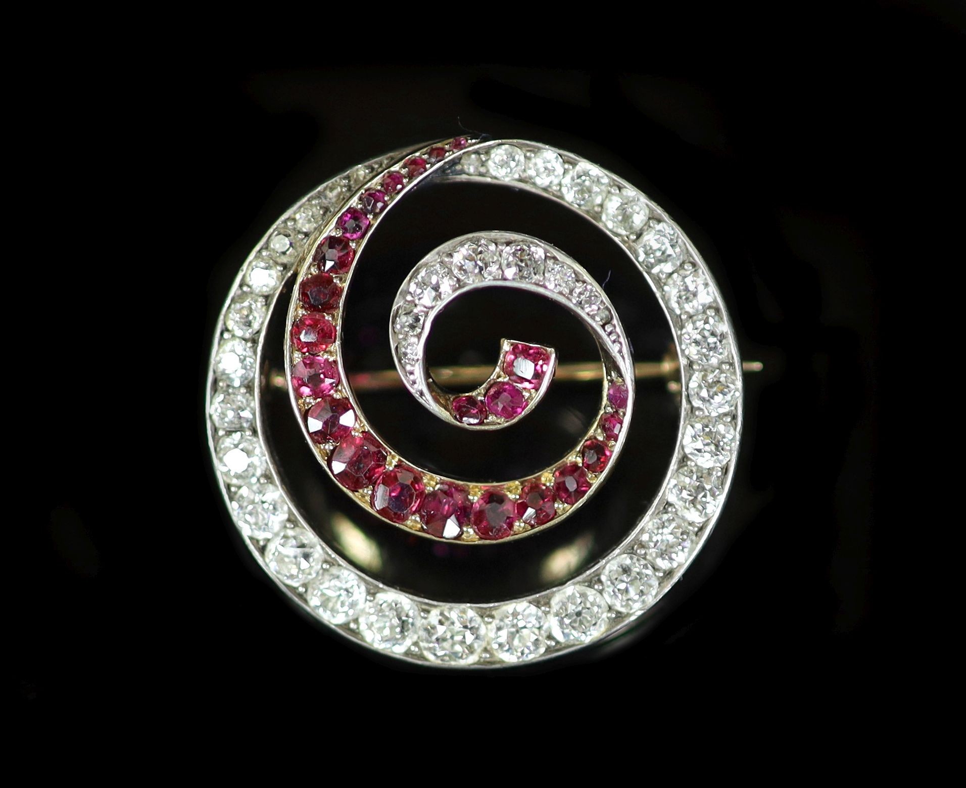 An early 20th century gold and silver, graduated ruby and diamond set open work whorl brooch